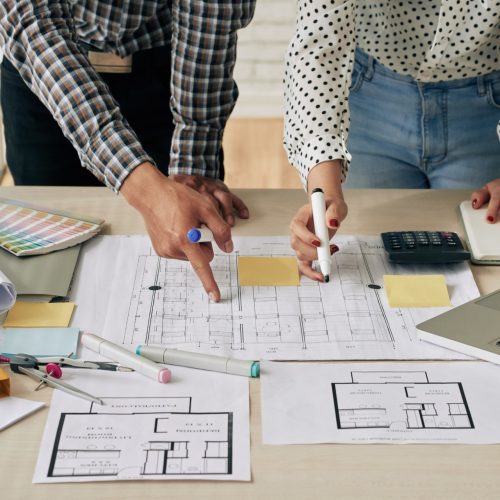 Discussing blueprint Cropped image of engineers discussing blueprint of the building